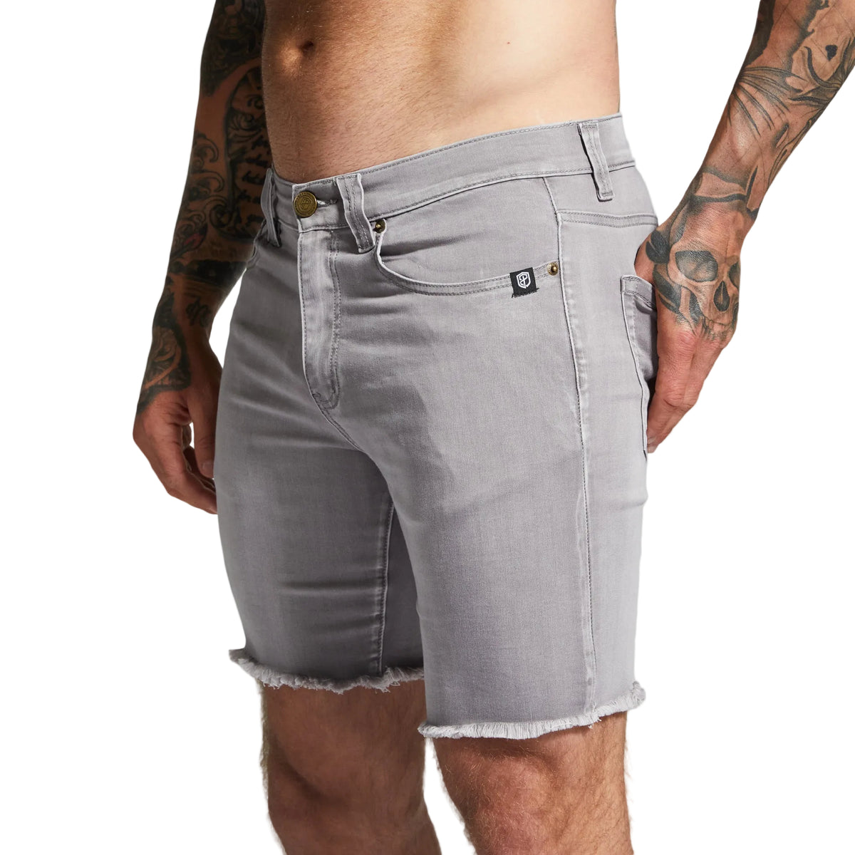 Gray denim shorts worn by a person with tattoos on a plain background