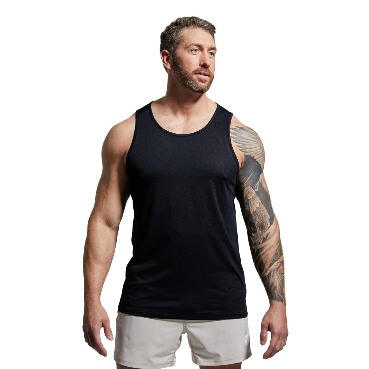 Man wearing a black tank top and white shorts against a gray background