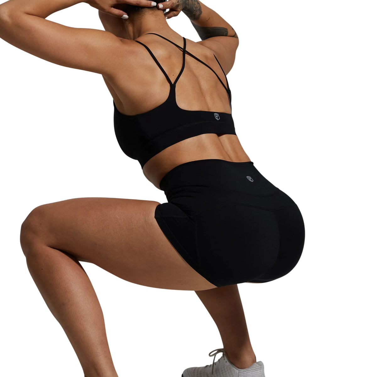 Person wearing a black sports bra and shorts on a gray background