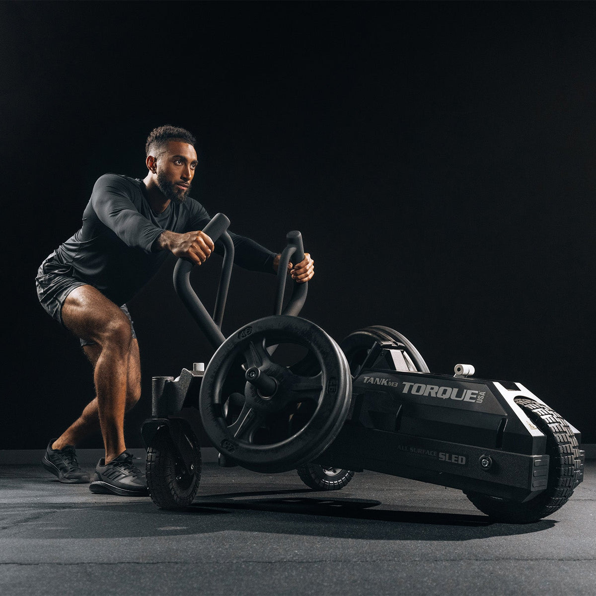 Person pushing a black go-kart on a dark background