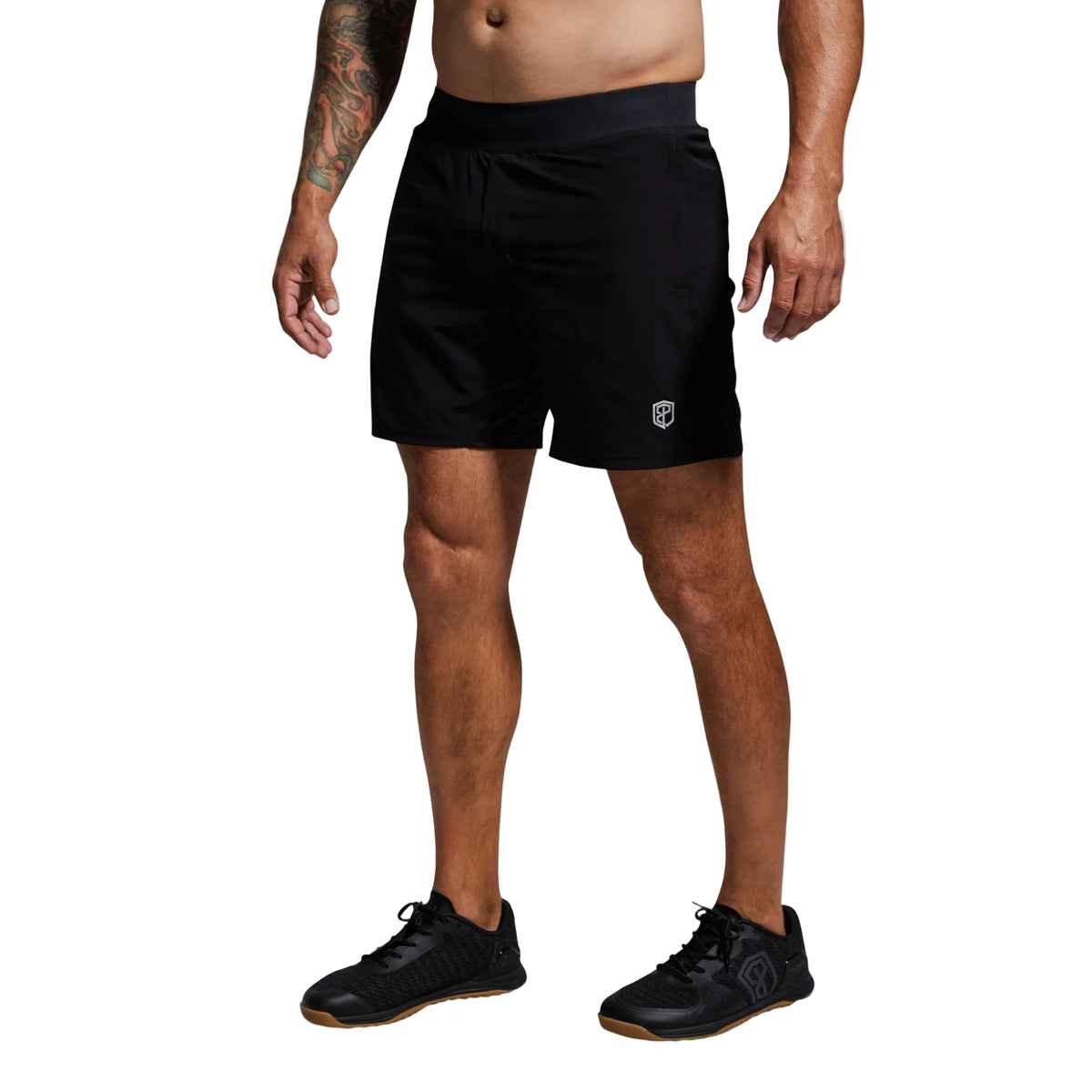 Person wearing black athletic shorts with a logo on a gray background