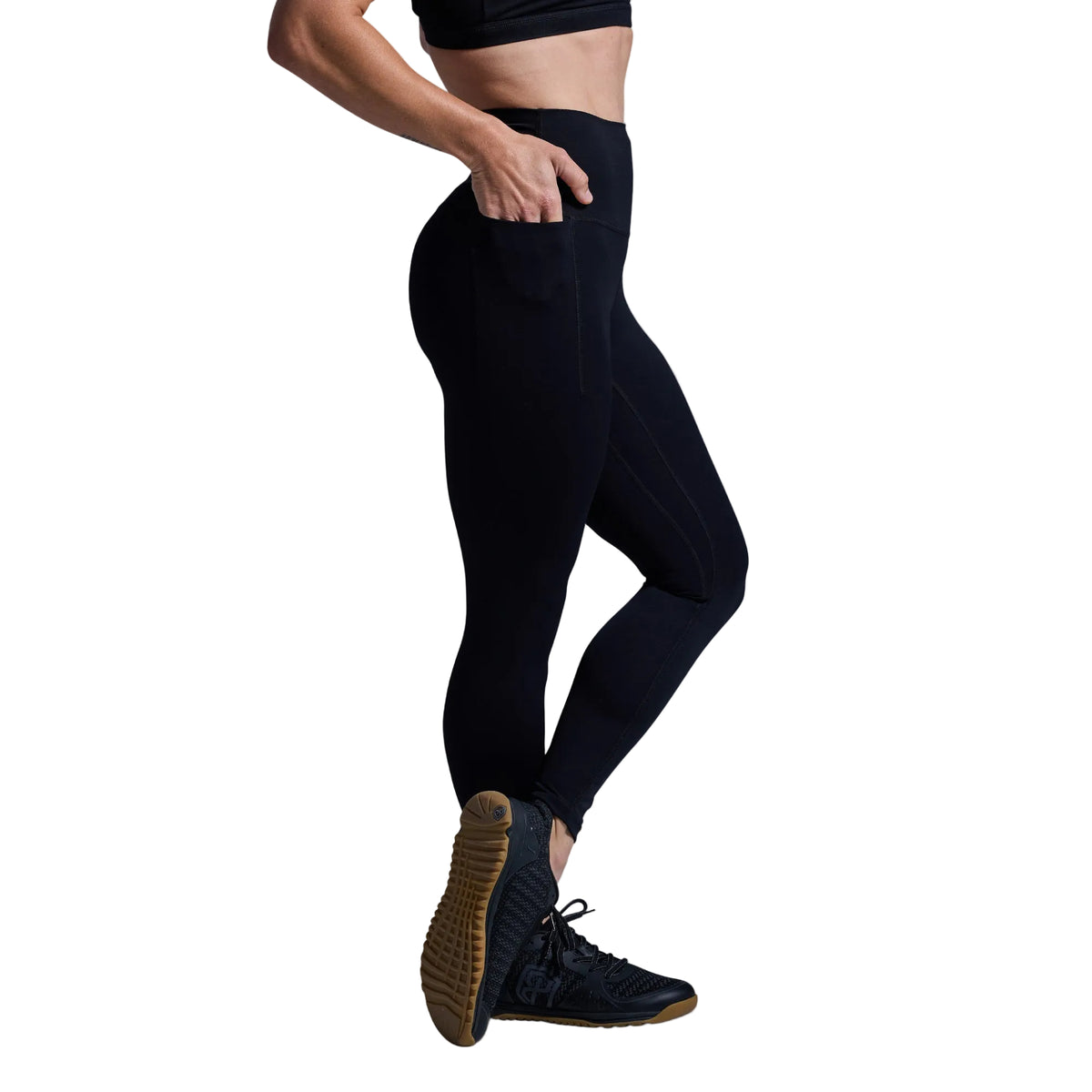Person wearing black leggings and dark shoes on a gray background