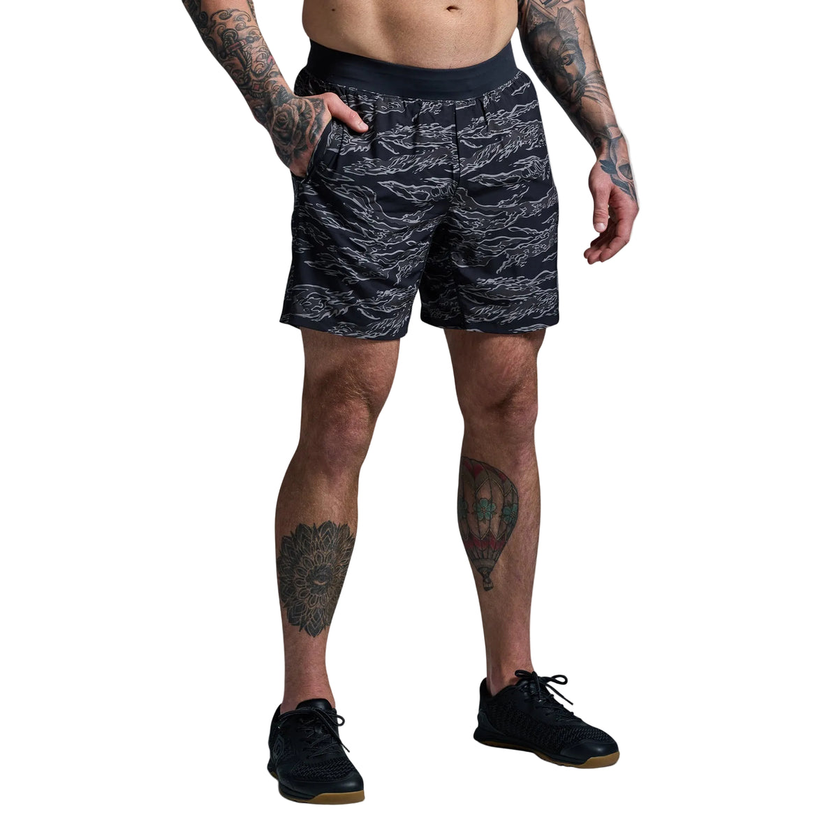 Person wearing black patterned shorts on a gray background