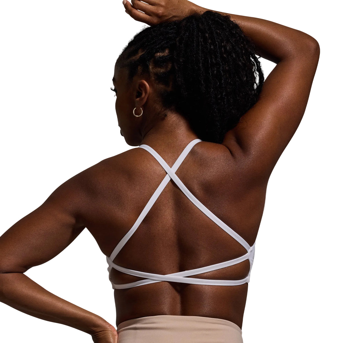 Woman wearing a white strappy top against a gray background