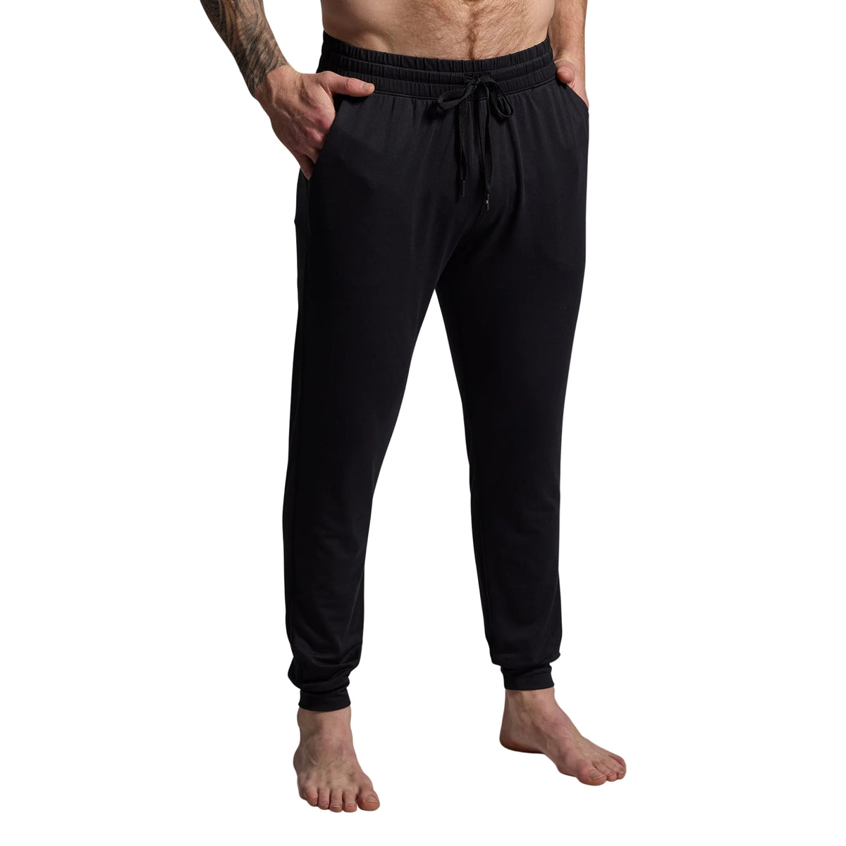 Person wearing black jogger pants on a gray background