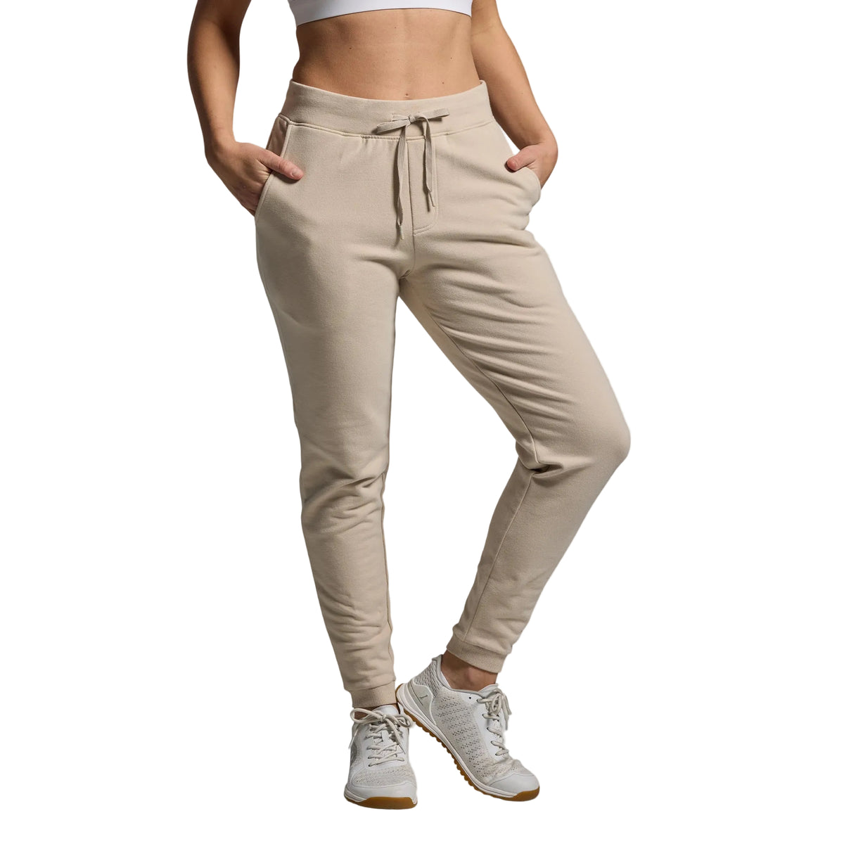 Beige jogger pants worn by a person on a gray background