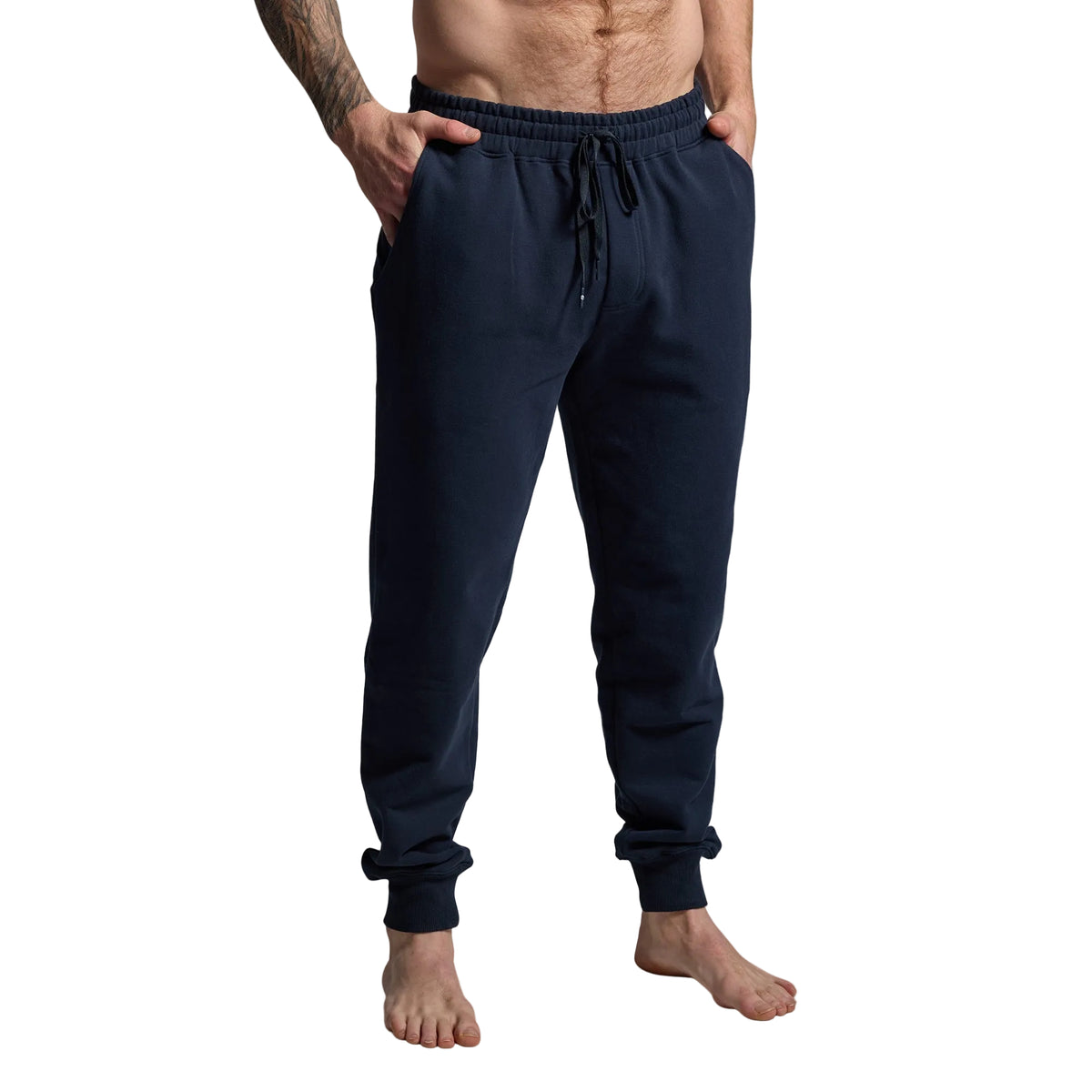 Person wearing navy blue jogger pants on a gray background
