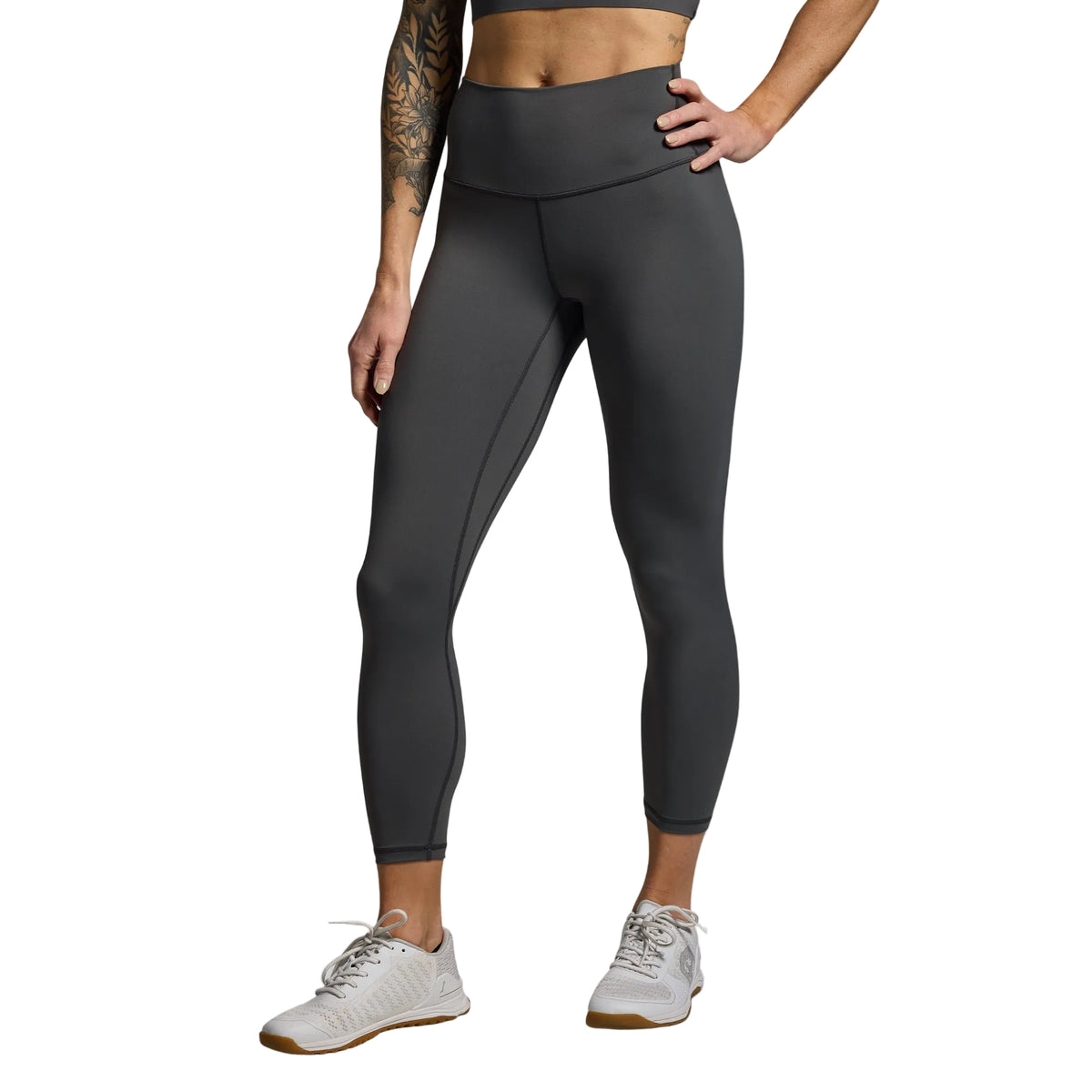 Person wearing dark gray leggings on a light gray background