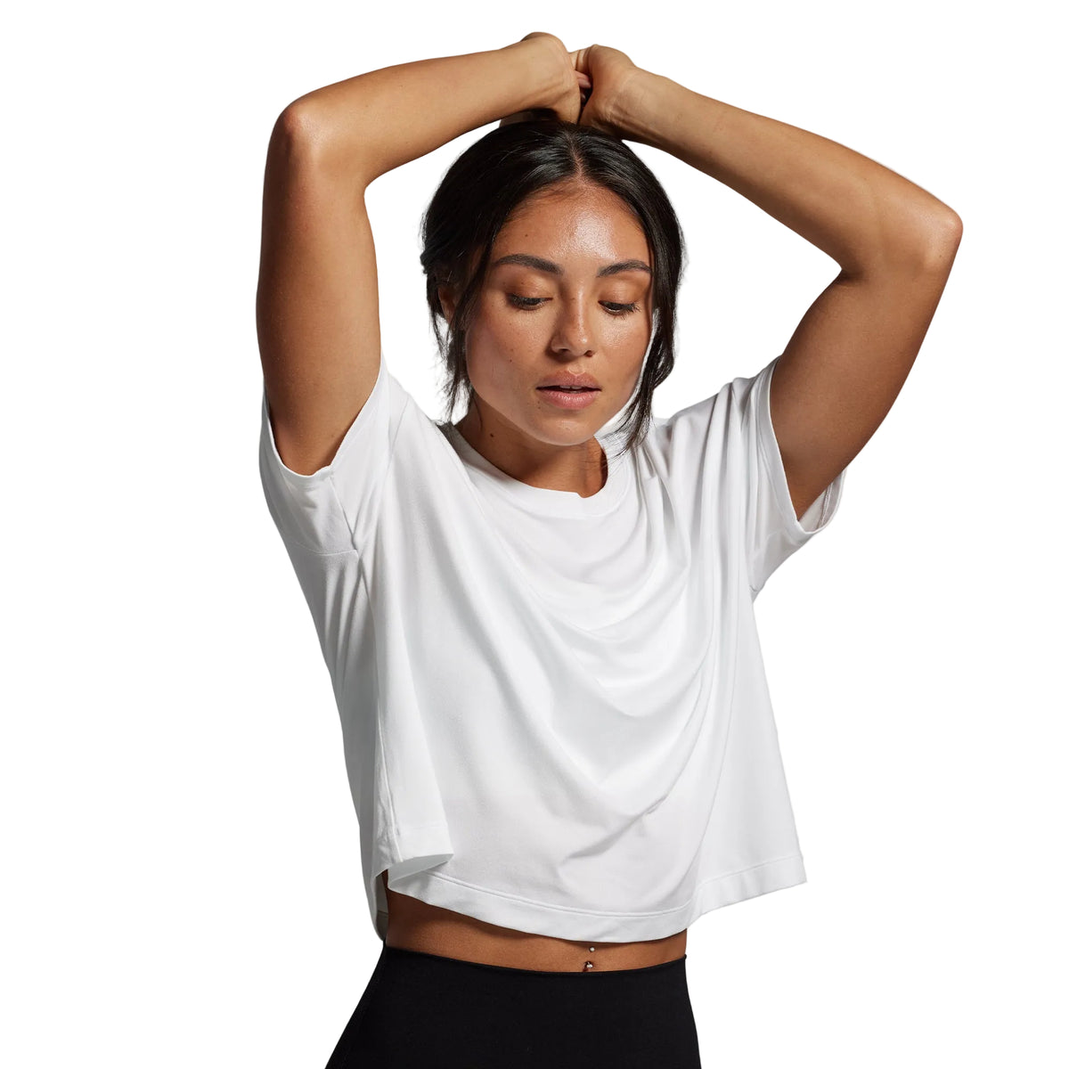 Woman wearing a white crop top and black pants against a gray background