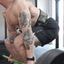 Man with tattoos lifting weights in a gym setting