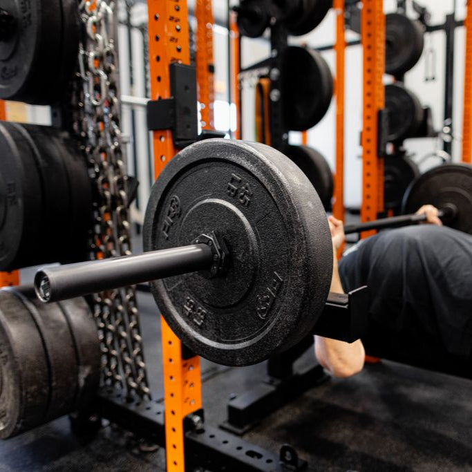Person performing a bench press with weights in a gym setting