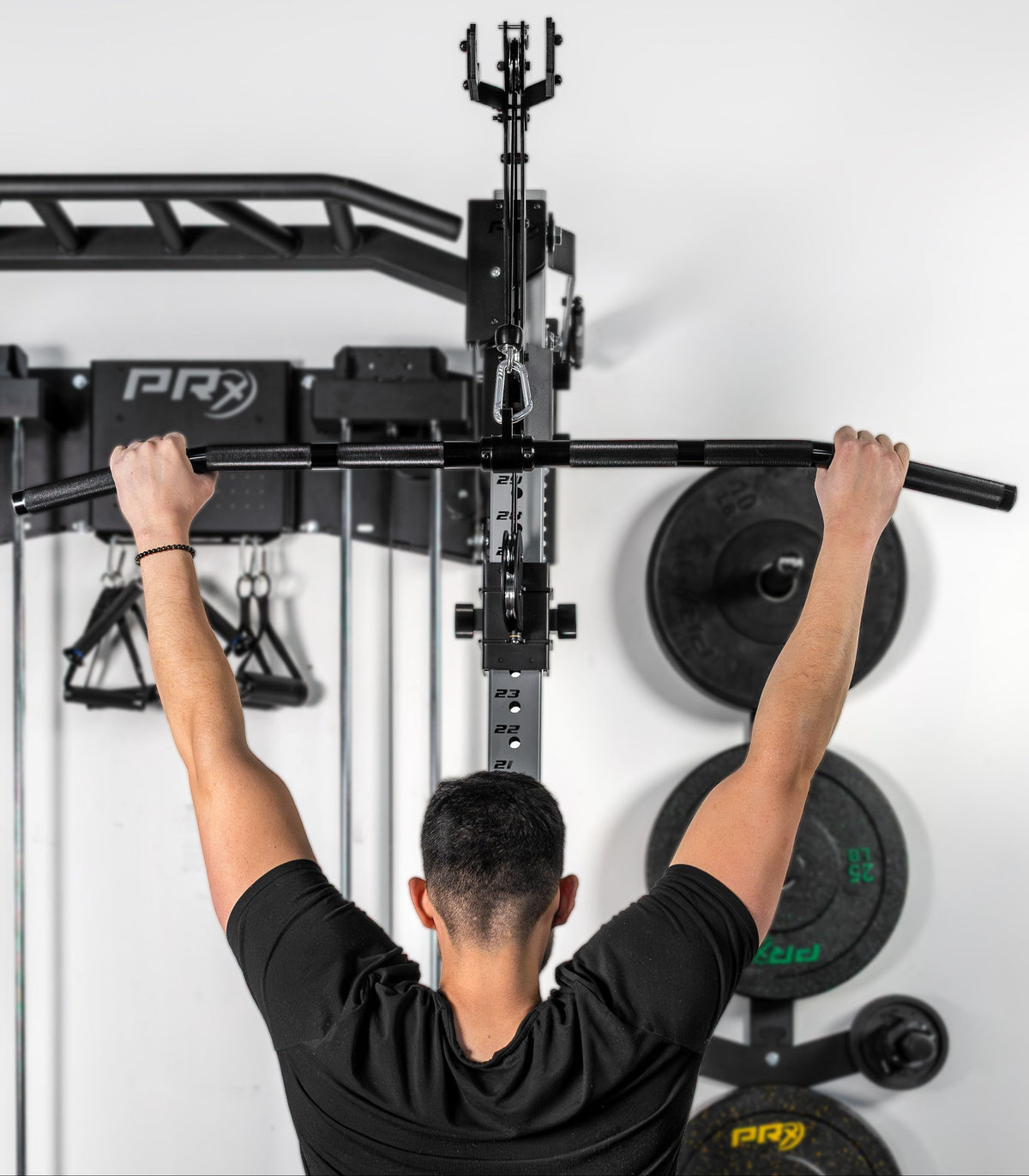 Person using a pull-up bar on a PRx fitness system against a white wall.