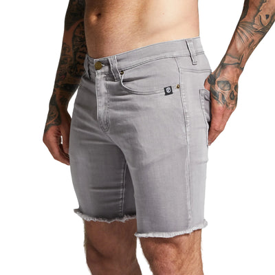 Gray denim shorts worn by a person with tattoos on a plain background
