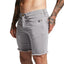 Gray denim shorts worn by a person with tattoos on a plain background