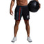 Person wearing black shorts with American flag design, holding a medicine ball on a gray background