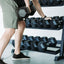 Man performing dumbbell row leaning against fully loaded dumbbell rack.