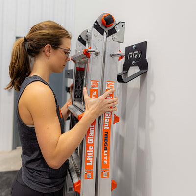 woman placing ladder on wall-mounted ladder storage