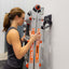 woman placing ladder on wall-mounted ladder storage