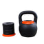 GRIND Adjustable Kettlebell on the floor with a stack of weights that get inserted into kettlebell for various weights.