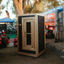 Wooden sauna tent outdoors with trees and equipment in the background