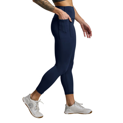Person wearing navy leggings and white sneakers on a gray background