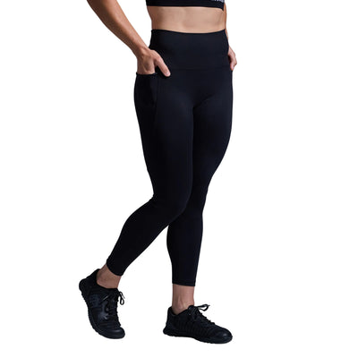 Person wearing black leggings and black sneakers on a gray background