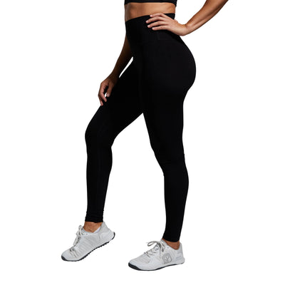 Person wearing black leggings and white sneakers on a gray background