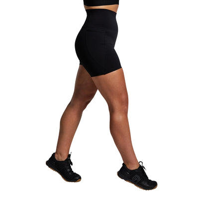 Person wearing black athletic shorts and shoes on a gray background