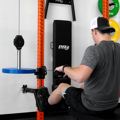 Person using a rowing machine in a gym setting with various equipment in the background.
