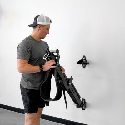Person using a piece of exercise equipment against a white wall.