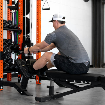 Man using a weight machine in a gym setting with weights and equipment around.