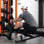 Man using a weight machine in a gym setting with weights and equipment around.