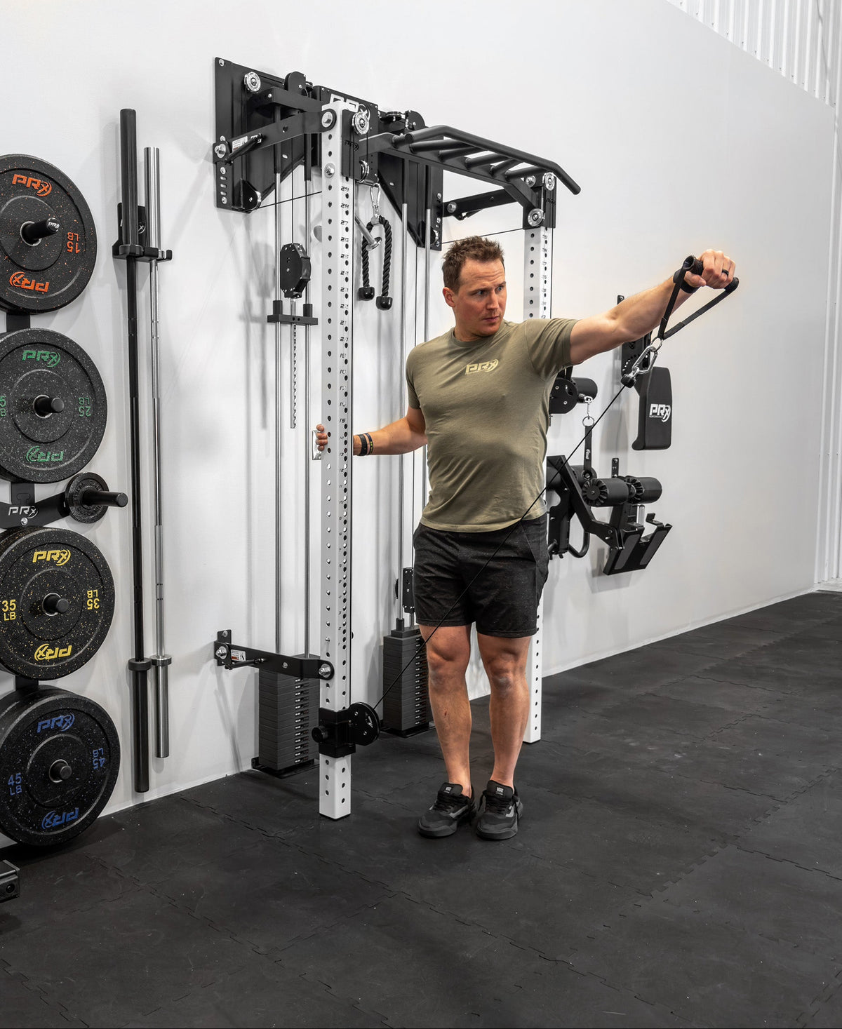 Person using a cable machine in a home gym setup with weights and equipment.