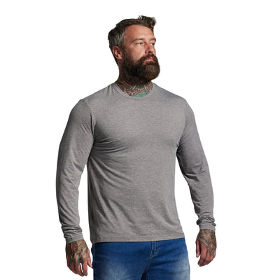 Man wearing a gray long-sleeve shirt and blue jeans against a plain background