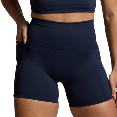 Navy blue athletic shorts worn by a person on a gray background