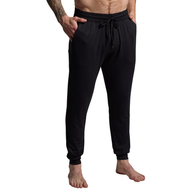 Person wearing black jogger pants on a gray background