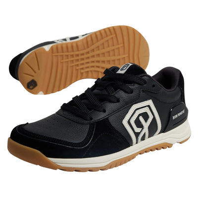 Black sneaker with brown sole on a gray background