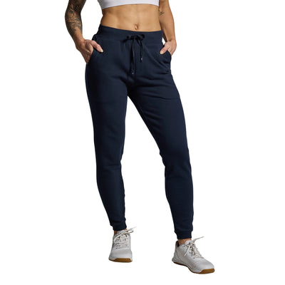 Person wearing navy jogger pants on a gray background