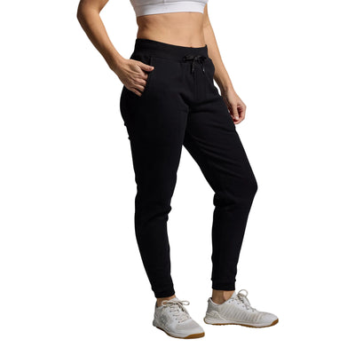 Person wearing black jogger pants and white sneakers on a gray background