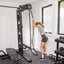 Woman using a pull-up bar in a home gym with weights and exercise equipment.