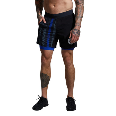 Person wearing black athletic shorts with blue accents on a gray background