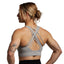 Woman wearing a gray sports bra with criss-cross straps on a plain background