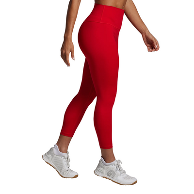 Person wearing red leggings and white sneakers on a gray background