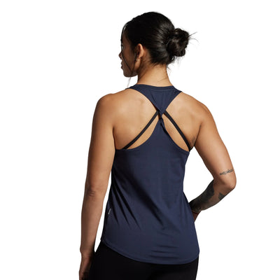 Woman wearing a navy blue tank top with thin straps on a gray background