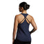 Woman wearing a navy blue tank top with thin straps on a gray background