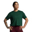 Woman wearing a green athletic shirt and maroon leggings on a gray background