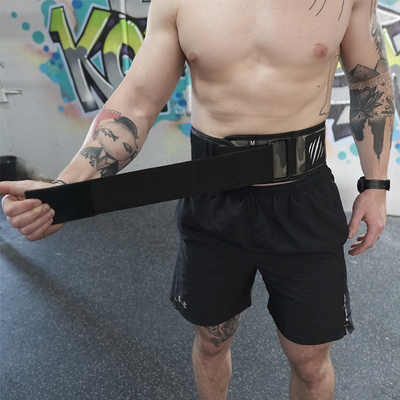 Person wearing a black weightlifting belt in an indoor setting with colorful graffiti.
