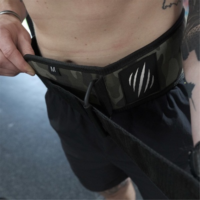 Person wearing a black weightlifting belt with a visible brand logo on a blurred background