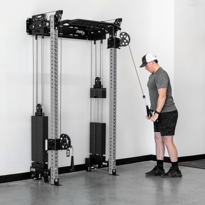 Person using a cable machine in a gym setting with a white wall background