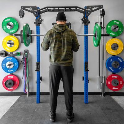 Person preparing to lift weights on a barbell in a gym setting with colorful weight plates.